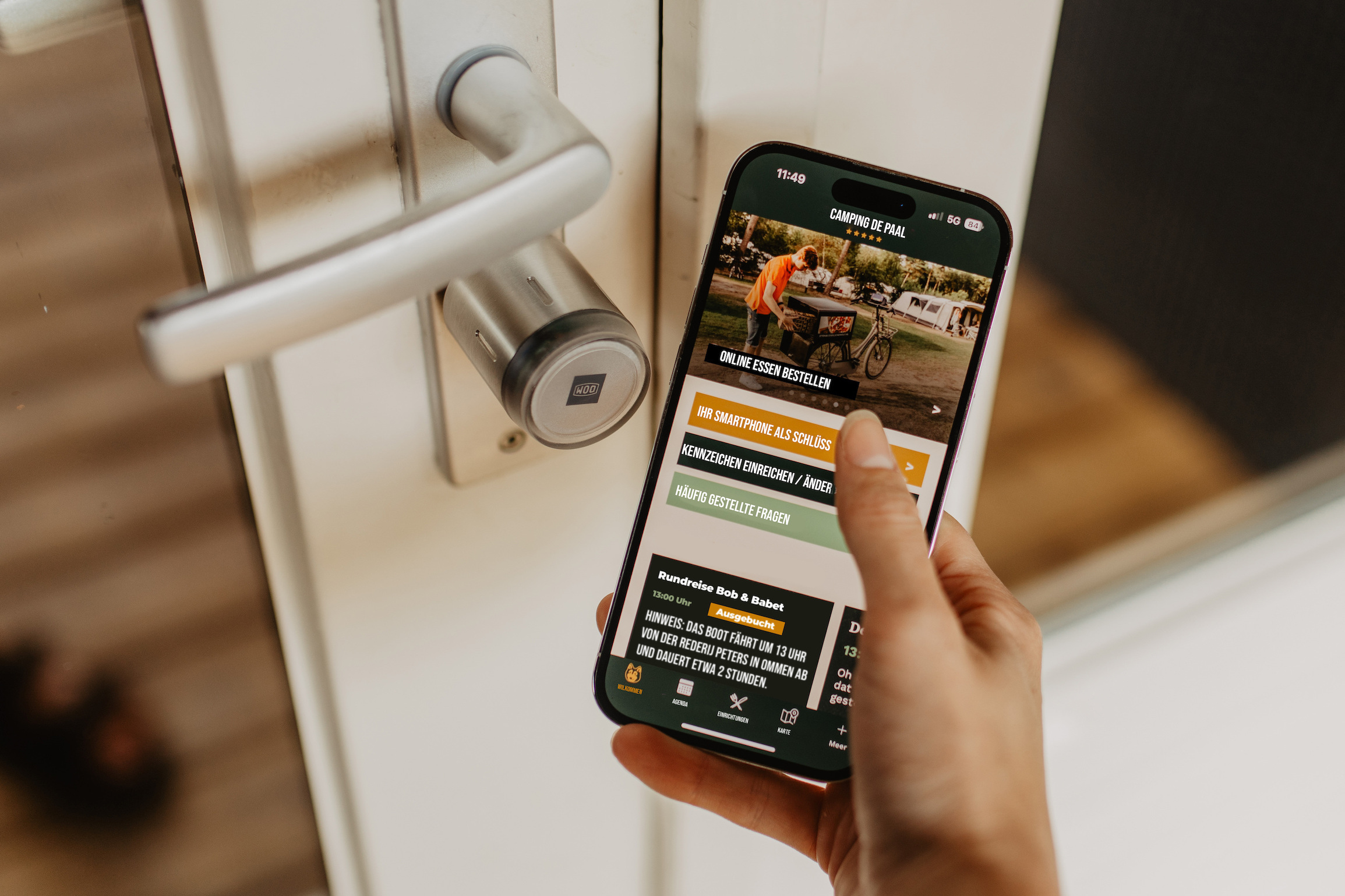 Handy vor Türschloss zur Unterkunft, das den digitalen Zugang zeigt